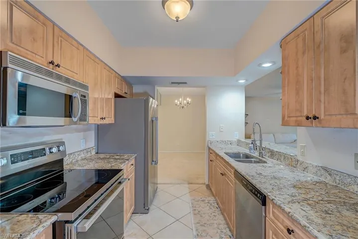 Kitchen featuring appliances with stainless steel finishes, pendant lighting, a chandelier, sink, and light tile floors