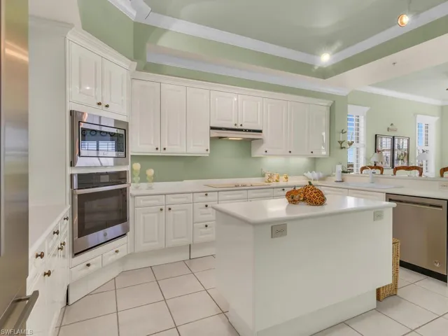 Kitchen featuring ornamental molding, a tray ceiling, white cabinets, and appliances with stainless steel finishes
