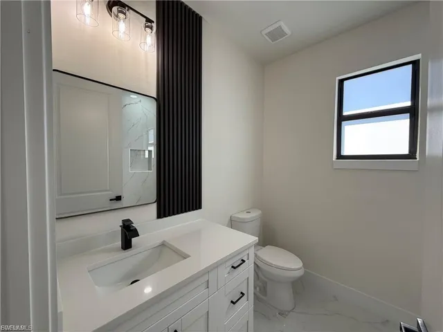 Full bath with vanity and light marble finish flooring