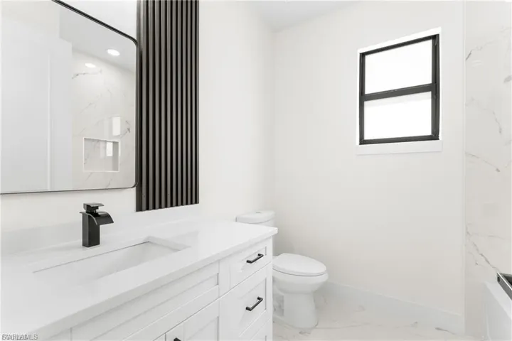 Bathroom featuring vanity, light marble finish floors, and recessed lighting