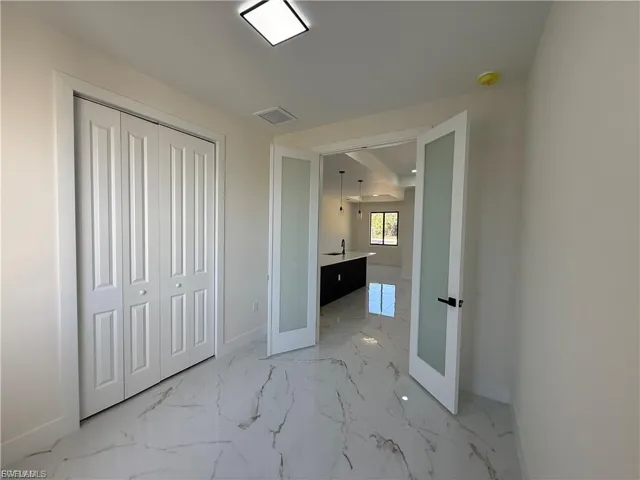 Unfurnished bedroom with light marble finish flooring, a closet, and french doors