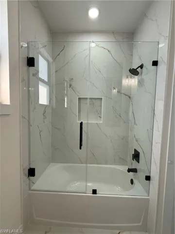Full bathroom featuring marble finish flooring and enclosed tub / shower combo