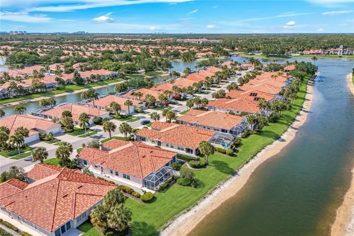 Aerial view showcasing the property's location within a community featuring waterways, green lawns, and mature palm trees