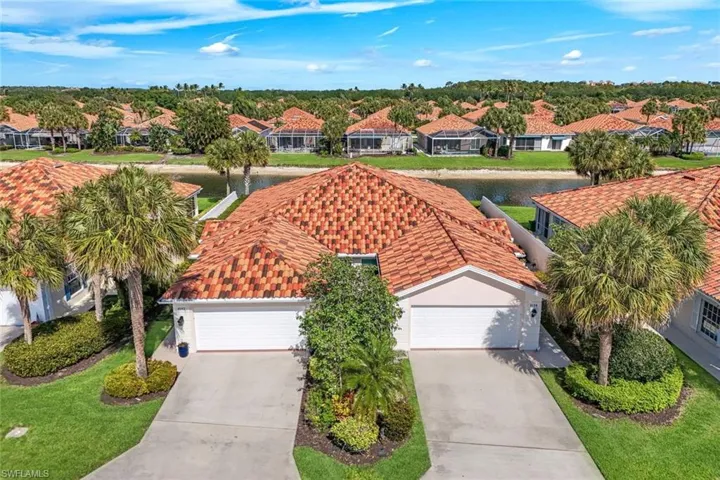 The community features properties with terracotta-tiled roofs and well-maintained green lawns, many of which are situated along a body of water