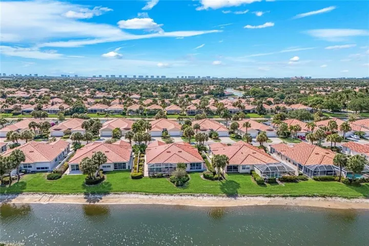 This property features a distinctive tile roof, two garage doors, and a lush green lawn with mature palm trees