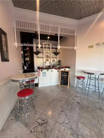 Bar featuring a wainscoted wall, crown molding, and an ornate ceiling