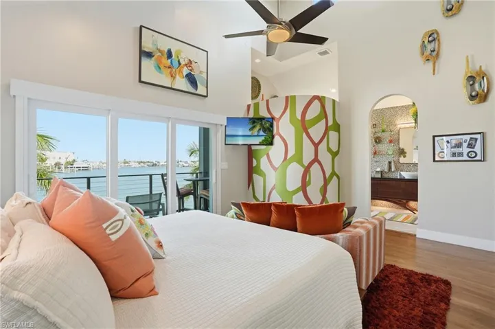 Bedroom featuring a high ceiling, wood finished floors, access to outside, arched walkways, and a ceiling fan - Virtually Edited Image