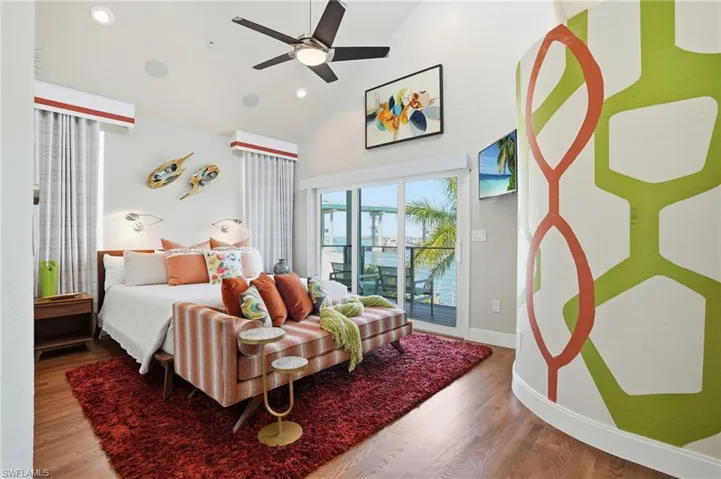 Bedroom with wood finished floors, lofted ceiling, access to outside, ceiling fan, and recessed lighting - Virtually Edited Image