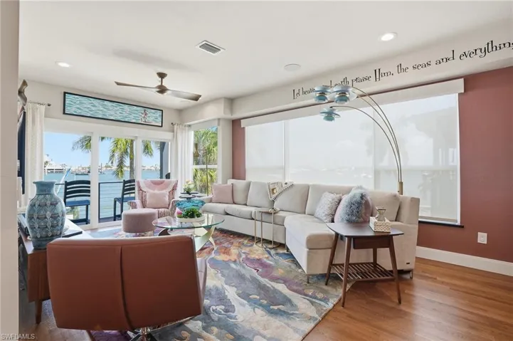 Living area with wood finished floors, recessed lighting, a water view, and ceiling fan - Virtually Edited Image