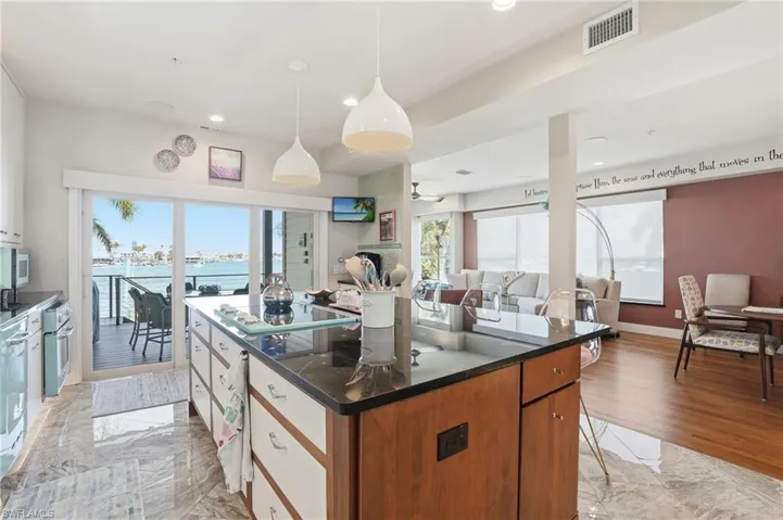 Kitchen featuring a center island, open floor plan, decorative light fixtures, wood finish cabinets, and stainless steel oven - Virtually Edited Image
