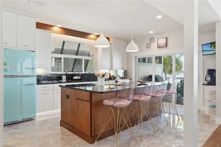 Two tone kitchen with freestanding refrigerator, tasteful backsplash, a kitchen island, two tone cabinetry, and decorative light fixtures - Virtually Edited Image