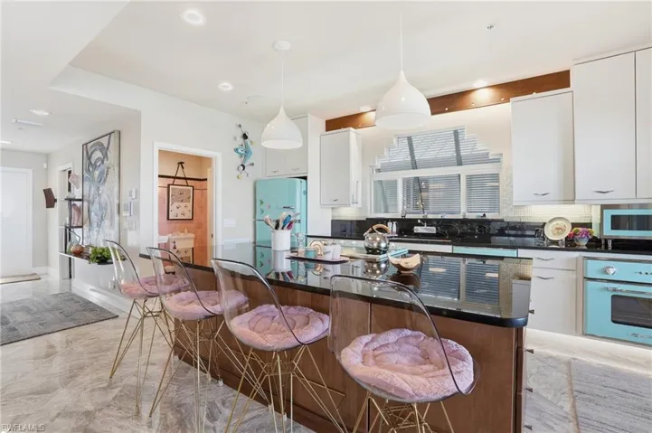 Kitchen with white cabinetry, decorative backsplash, a kitchen island, wall oven, and pendant lighting - Virtually Edited Image