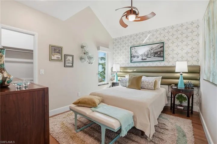 Bedroom featuring wallpapered walls, light wood-style floors, lofted ceiling, an accent wall, and ceiling fan - Virtually Edited Image