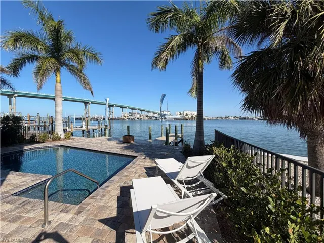 Outdoor pool with a water view, a boat dock, and boat lift