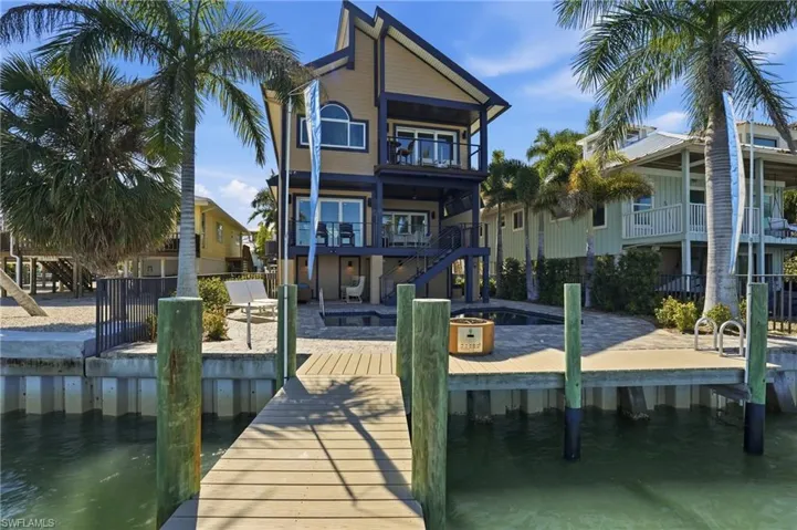 Dock area with a water view, a patio area, a balcony, and a swimming pool - Virtually Edited Image