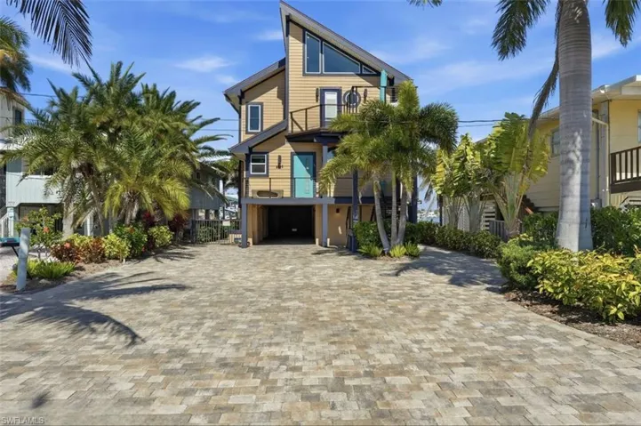 View of front of home featuring a balcony, driveway, and a garage - Virtually Edited Image