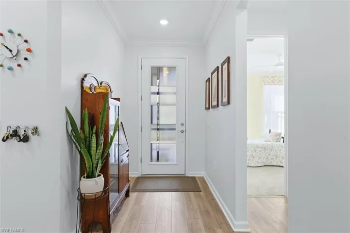 Entryway featuring a white door with glass panels, wood-finish flooring, crown molding, and recessed lighting