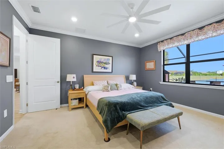 Neutral-toned bedroom featuring carpeted flooring, crown molding, recessed lighting, a multi-blade ceiling fan, and a large window with black framing