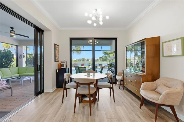 Dining area featuring wood-finish flooring, crown molding, a multi-light contemporary chandelier, and large sliding glass doors