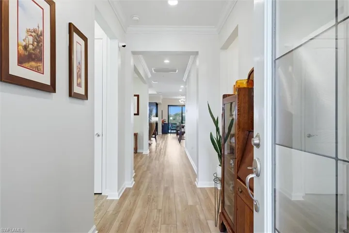 Entryway featuring wood-finish flooring, crisp crown molding, and a multi-pane glass entry door