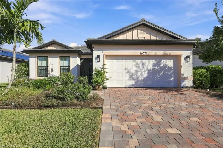 Single-story residence featuring a multi-toned paver driveway, stucco exterior, gabled roofline with decorative board-and-batten siding, and an integrated two-car garage