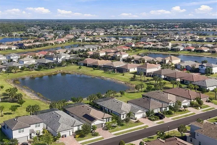 Aerial perspective of a suburban neighborhood featuring paved streets, multi-level residential homes, tiled roofing, and communal water features