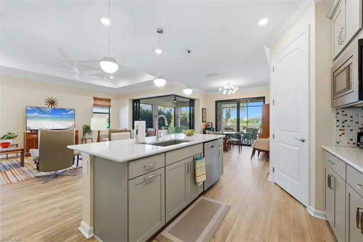 Kitchen featuring a center island with quartz countertops, custom cabinetry, recessed lighting, wood-finish flooring, and multi-panel sliding glass doors