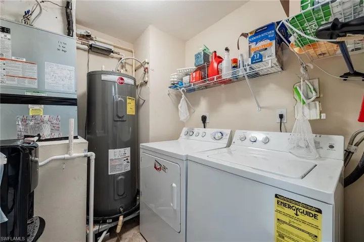 Laundry area featuring electric water heater, washer and dryer, and heating unit