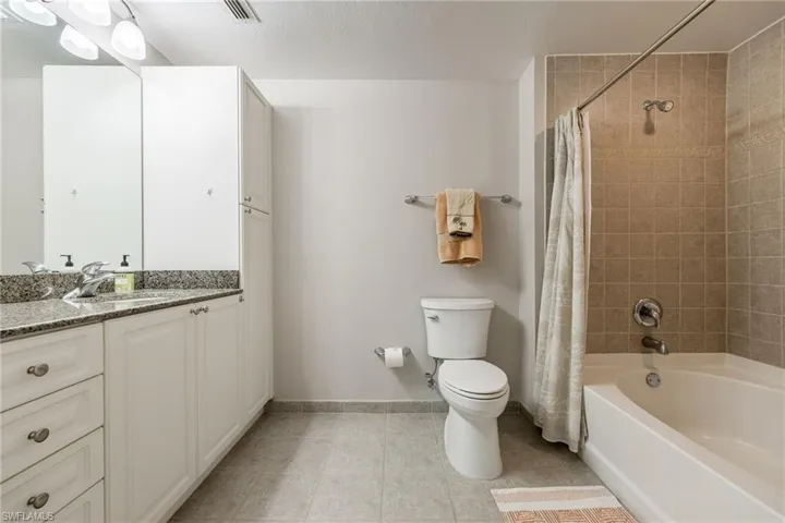 Bathroom with vanity, shower / bath combo with shower curtain, and light tile patterned floors
