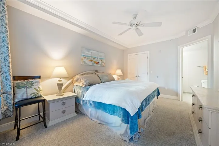 Bedroom with a closet, light colored carpet, crown molding, and ceiling fan