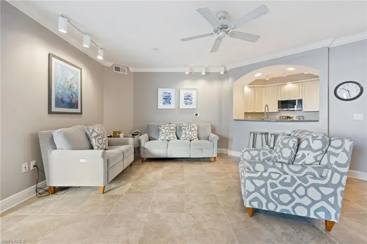 Living room with track lighting, ornamental molding, a ceiling fan, and light tile patterned floors