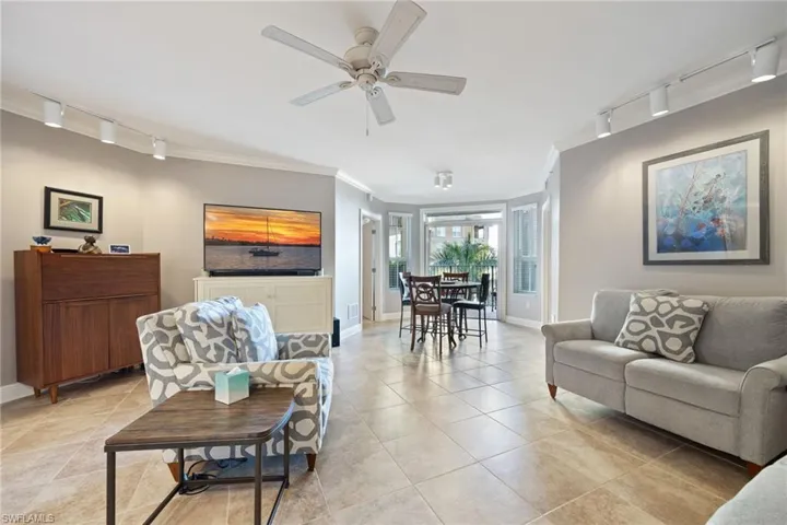 Living room with track lighting, crown molding, ceiling fan, and light tile patterned floors