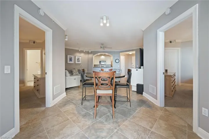 Dining space featuring light colored carpet, ornamental molding, light tile patterned floors, and ceiling fan