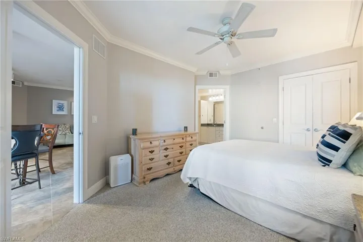 Bedroom with light carpet, ornamental molding, a closet, ceiling fan, and ensuite bath