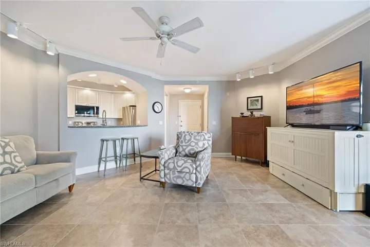 Living area with rail lighting, ornamental molding, arched walkways, and a ceiling fan