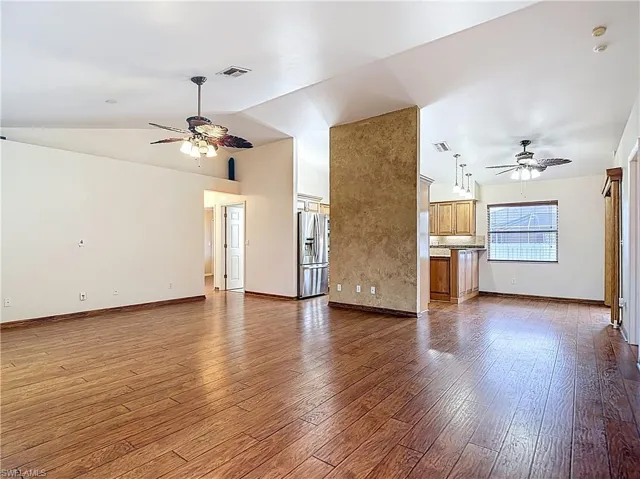 Unfurnished living room with ceiling fan, light wood finished floors, and vaulted ceiling