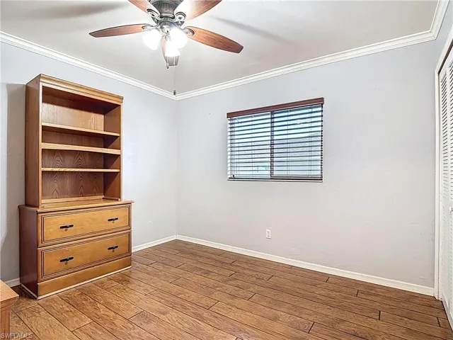 Unfurnished bedroom featuring crown molding, hardwood / wood-style floors, and a ceiling fan
