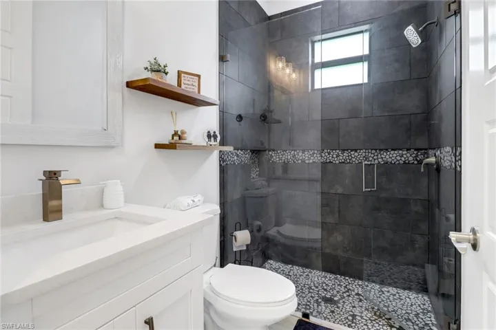 Bathroom with vanity, tiled shower, and toilet