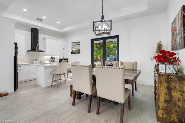 Dining space featuring a raised ceiling, light wood-type flooring, and an inviting chandelier