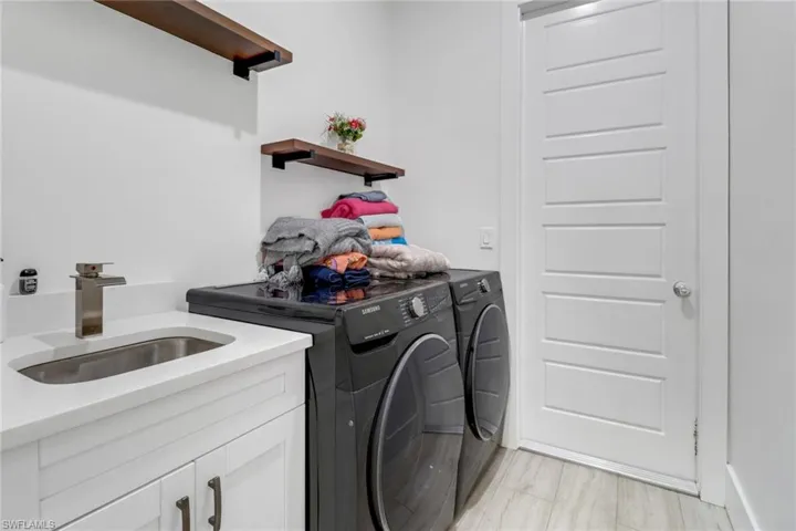 Laundry room featuring washing machine and clothes dryer, sink, and cabinets
