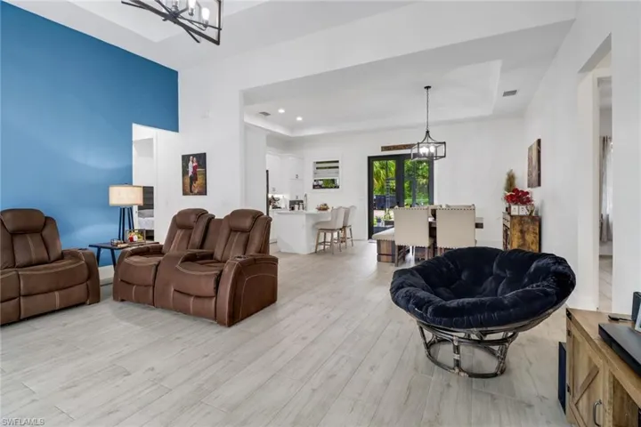 Living room with a chandelier, light hardwood / wood-style flooring, and a raised ceiling