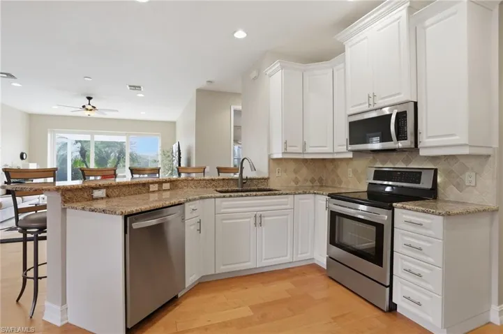 Kitchen with a breakfast bar area, stainless steel appliances, dark stone counters, and recessed lighting