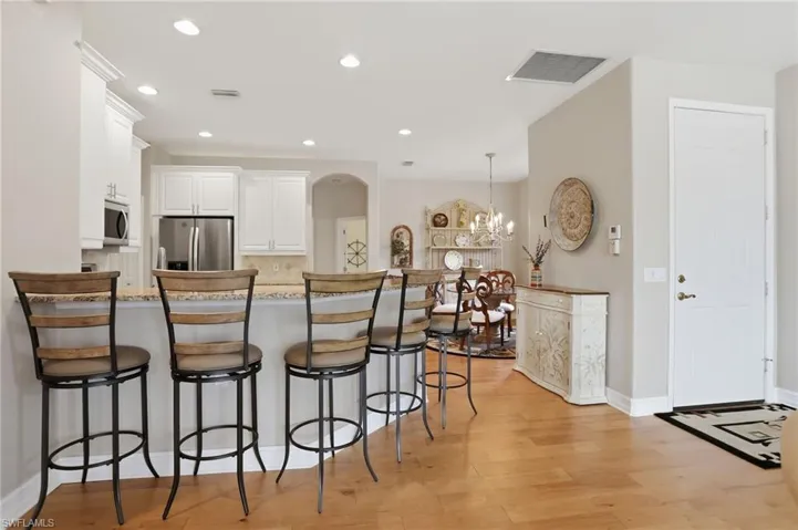 Kitchen with white cabinets, a kitchen bar, stainless steel appliances, a peninsula, and a chandelier
