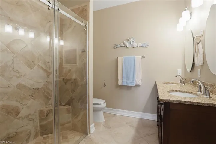 Full bathroom featuring double vanity and a stall shower