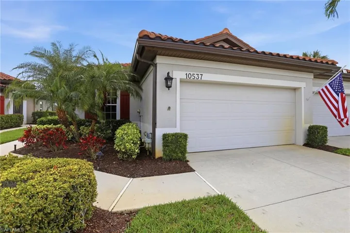 View of front facade featuring a garage, concrete driveway, a tile roof, and stucco siding