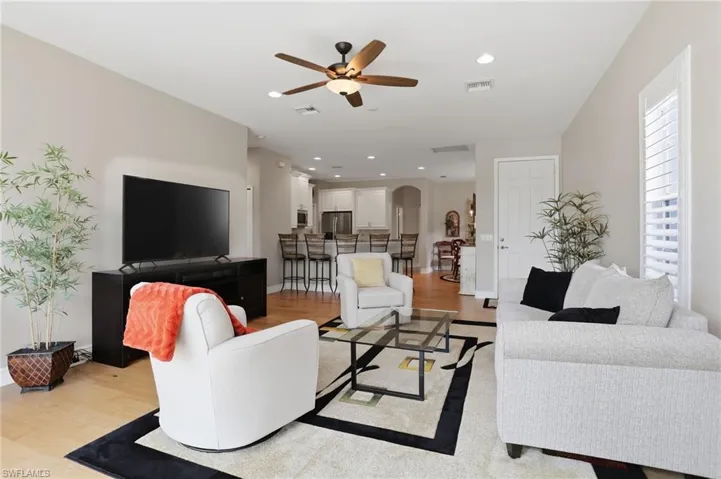 Living area featuring light wood-style floors, arched walkways, a ceiling fan, and recessed lighting