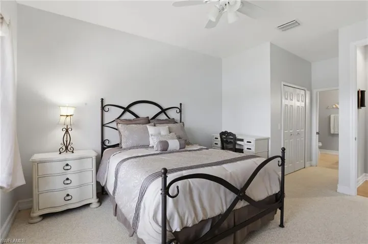 Bedroom featuring light colored carpet, a closet, ceiling fan, and connected bathroom