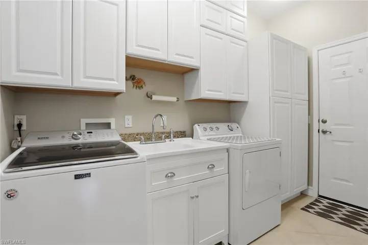 Laundry room with light tile patterned floors, cabinet space, and separate washer and dryer