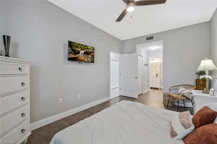 Bedroom with dark wood-style floors, ensuite bath, and ceiling fan