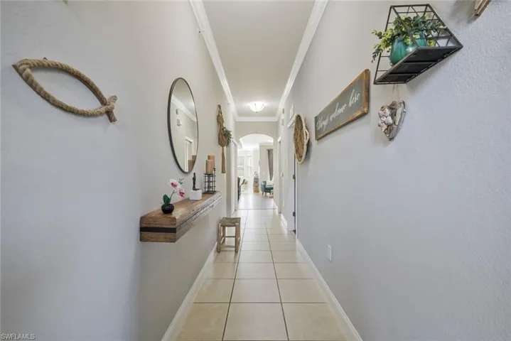 Hall featuring crown molding, arched walkways, and light tile patterned floors